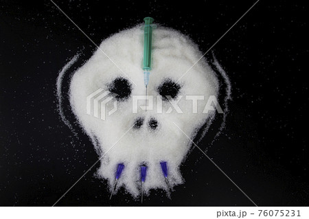 Sugar in the form of a skull on a black background. The concept of the harmful effects of granulated sugar on the human body and dependence on sweets. 76075231