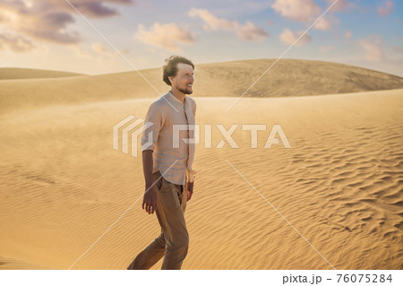 Man traveling in the desert. Sandy dunes and blue sky on sunny summer day. Travel, adventure, freedom concept. Tourism reopens after quarantine COVID 19 76075284