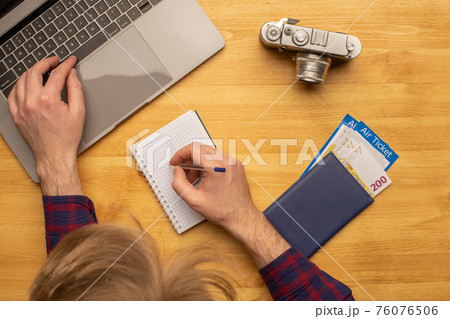 Top view of man working at desk making travel or vacation plan Top view of man working at desk making travel or vacation plan 76076506