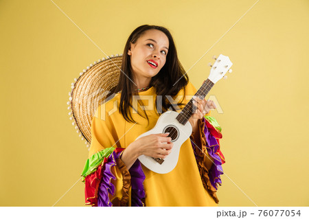 Young pretty girl in bright garment and sombrero isolated over yellow background 76077054
