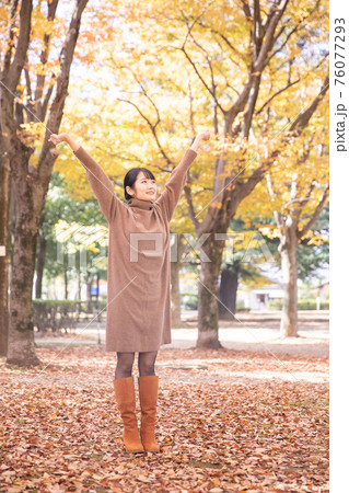 秋の公園にいる女性 76077293