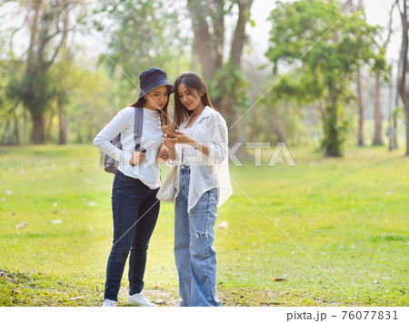 Two young female travellers looking on smartphone while finding their destination Two young female travellers looking on smartphone while finding their destination 76077831