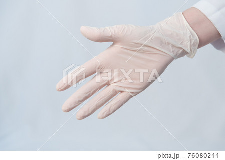 The doctor's hand is extended for a handshake. A protective medical glove is worn on the hand. Glove mode. Close-up. Virus protection concept The doctor's hand is extended for a handshake. A protective medical glove is worn on the hand. Glove mode. Close-up. Virus protection concept 76080244