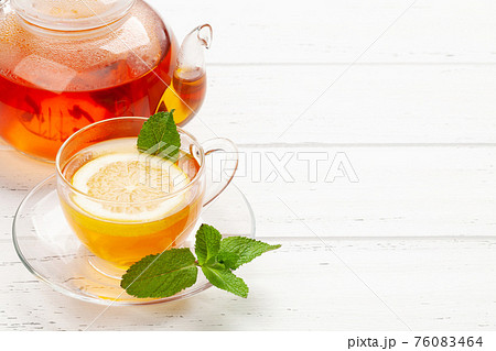 Herbal tea with mint and lemon. Tea cup and teapot 76083464