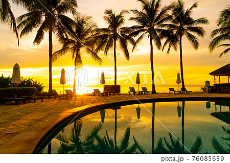 Umbrella and chair around swimming pool in hotel resort with sunrise in morning 76085639