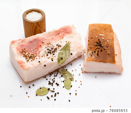 raw lard two pieces and salt, spices and bay leaf on white background, pork fat 76085655
