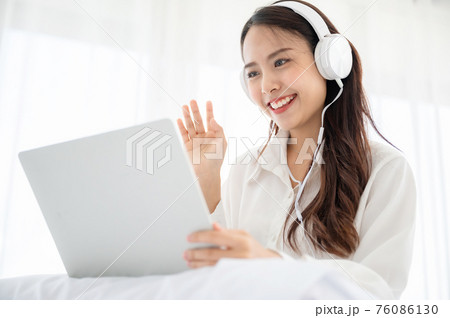 Happy beautiful young asian woman working on computer laptop and sitting on bed in house Happy beautiful young asian woman working on computer laptop and sitting on bed in house 76086130