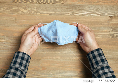 hands with handmade breathing mask on a wooden background, checkered shirt in rustic style, health care prevention of coronavirus infection, as well as other viruses and pollution hands with handmade breathing mask on a wooden background, checkered shirt in rustic style, health care prevention of coronavirus infection, as well as other viruses and pollution 76086922