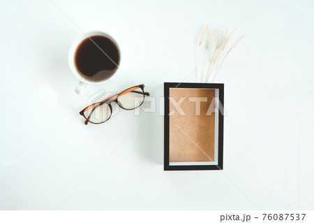 Black frame mockup, glasses and coffee  with a grass flowers in a on a white background. 76087537