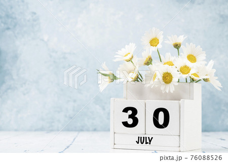 cube calendar for July with daisy flowers over blue cube calendar for July with daisy flowers over blue 76088526