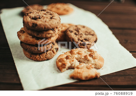 Chocolate cookies on parchment paper. Broken biscuits on a wooden table. Selective focus. 76088919