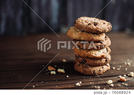 Cookies with chocolate worth a stack on a wooden table in a rustic style. Crumbs from biscuits on wooden boards. Selective focus Cookies with chocolate worth a stack on a wooden table in a rustic style. Crumbs from biscuits on wooden boards. Selective focus 76088924