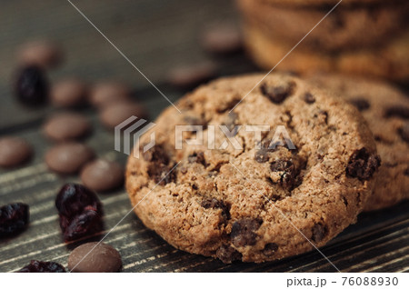 A stack of oatmeal cookies with chocolate pieces and candied fruits lies on a wooden table. Rustic table. Vintage toning. Dietary useful cookies without gluten. Copy space. A stack of oatmeal cookies with chocolate pieces and candied fruits lies on a wooden table. Rustic table. Vintage toning. Dietary useful cookies without gluten. Copy space. 76088930