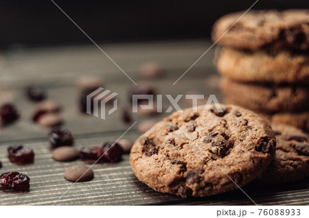 A stack of oatmeal cookies with chocolate pieces and candied fruits lies on a wooden table. Rustic table. Vintage toning. Dietary useful cookies without gluten. Copy space. 76088933