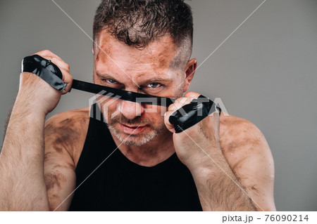 on a gray background stands a battered man in a black T shirt looking like a fighter and preparing for a fight on a gray background stands a battered man in a black T shirt looking like a fighter and preparing for a fight 76090214