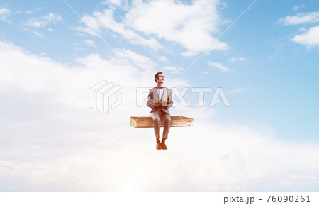 Young businessman or student floating in blue sky and studying the science Young businessman or student floating in blue sky and studying the science 76090261