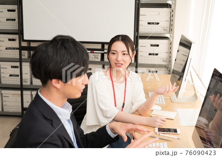 パソコンの画面を見ながら上司からアドバイスを受ける女性社員 76090423