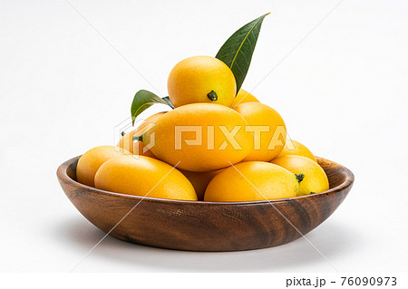 Side view of freshly harvested ripe Marian Plum fruit in wooden bowl. 76090973