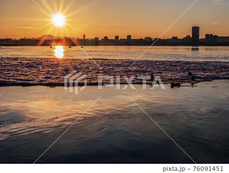 Sunset over the river. Ice-drift. Dusk cityscape. 76091451