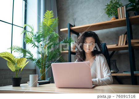 cheerful female manager working with laptop and typing at home office 76091516