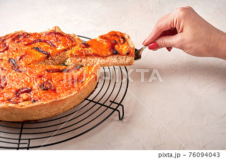 Woman's hand holds on a shoulder blade piece of homemade quiche  76094043