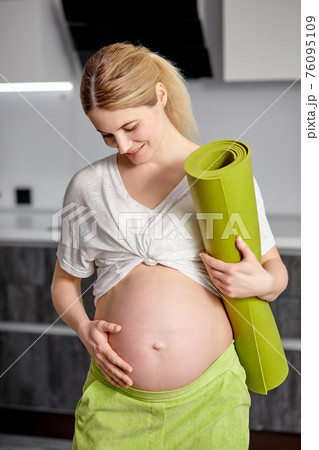 Portrait Of Cute Pregnant Female Stroking Touching Belly, Mom-to-be Expecting Baby, Stand With Fitness Mat After Yoga Portrait Of Cute Pregnant Female Stroking Touching Belly, Mom-to-be Expecting Baby, Stand With Fitness Mat After Yoga 76095109