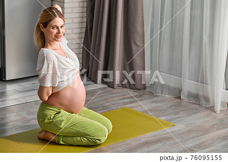 side view on pregnant woman stretching body at home, going to do yoga exercises on floor 76095155