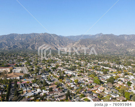 Aerial view above Pasadena neighborhood with mountain on the background. California 76095984
