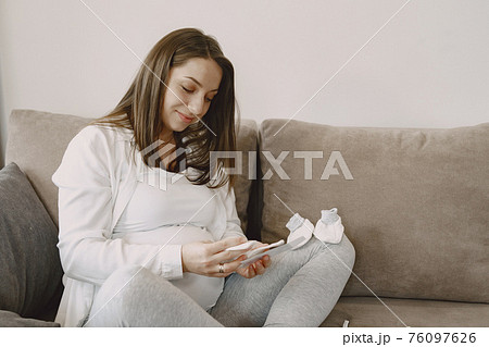 Pregnant woman looks at photo 76097626