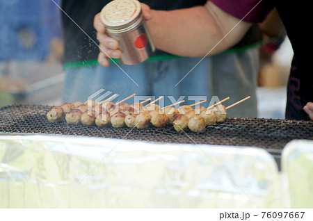 つくね焼にコシヨウを振るおじさんの手 76097667