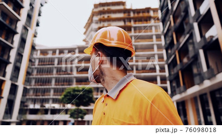 Protection coronavirus, covid-19, air pollution, dust, allergies in construction and manufacturing. Employee health protection. Builder puts on helmet on construction site wears protective mask kn 95 Protection coronavirus, covid-19, air pollution, dust, allergies in construction and manufacturing. Employee health protection. Builder puts on helmet on construction site wears protective mask kn 95 76098018