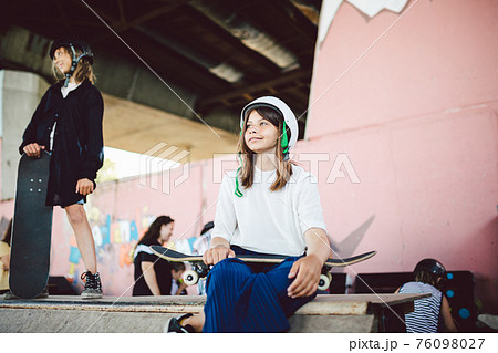 Schoolgirl after school. Portrait confident, cool young female skateboarder at outdoor skate park. Urban girl with skate board on half pipe ramp. lifestyle. Sports club for children. Skateboard club Schoolgirl after school. Portrait confident, cool young female skateboarder at outdoor skate park. Urban girl with skate board on half pipe ramp. lifestyle. Sports club for children. Skateboard club 76098027