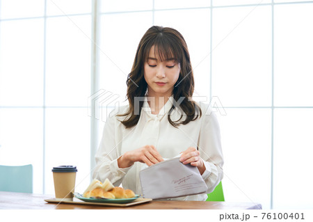カフェでマスクをして食事をする若い女性 76100401