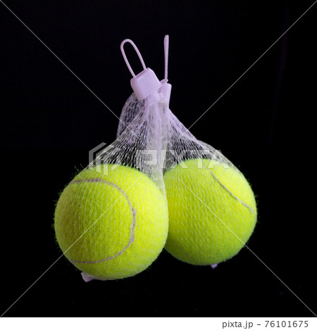 Yellow tennis ball in network package on black background 76101675