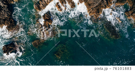 A dangerous sea wave crashes into the rocky coast with spray and foam before the storm. A dangerous sea wave crashes into the rocky coast with spray and foam before the storm. 76101883