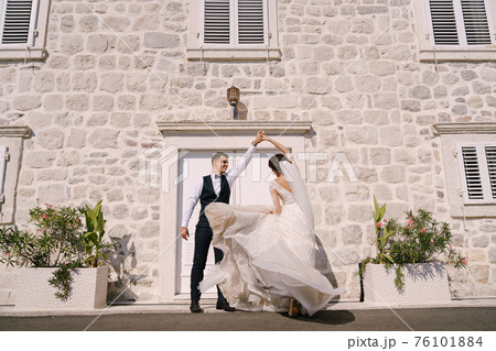 Fine-art wedding photo in Montenegro, Perast. The bride and groom are dancing against the backdrop of an old white house. 76101884