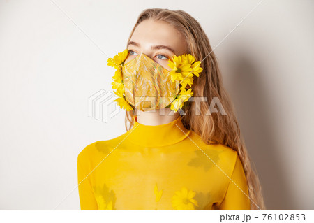 Woman in mask with yellow flowers in studio 76102853