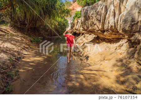 Boy tourist on the Fairy stream among the red dunes, Muine, Vietnam. Vietnam opens borders after quarantine COVID 19 Boy tourist on the Fairy stream among the red dunes, Muine, Vietnam. Vietnam opens borders after quarantine COVID 19 76107354