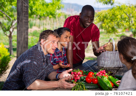 Farmers talking while sitting at table in the garden Farmers talking while sitting at table in the garden 76107421