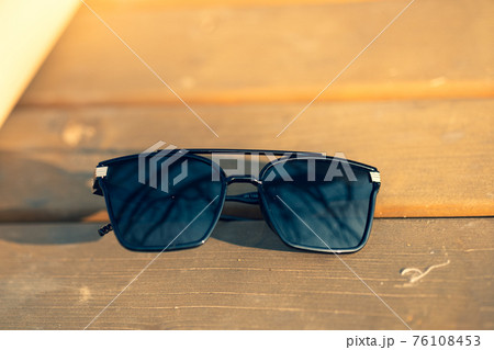 Oversized sunglasses model with big black lenses shoot outside in nature in a summer day closeup . Selective focus 76108453