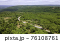 Aerial view from drone going through road on the mountain with green forest. View from the drone of the curve road. 76108761