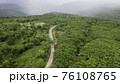 Aerial view from drone going through road on the mountain with green forest. View from the drone of the curve road. 76108765
