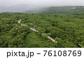 Aerial view from drone going through road on the mountain with green forest. View from the drone of the curve road. 76108769