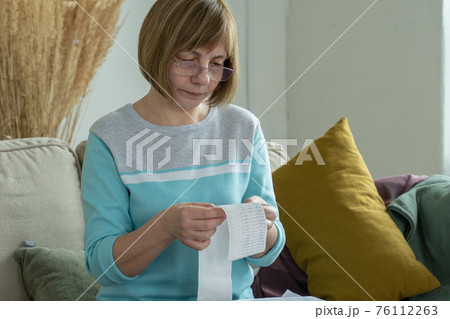 Woman looking a check from a supermarket. Expense tracking and budgeting 76112263