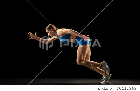 Active woman, track athlete training isolated over black studio background. Active woman, track athlete training isolated over black studio background. 76112565