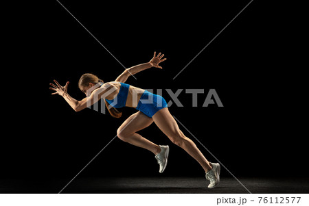 Sportive woman, track athlete training isolated over black studio background. 76112577