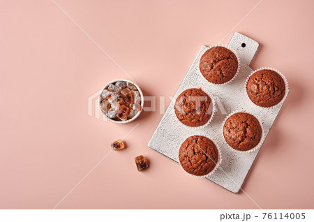 Homemade chocolate cupcakes in baking paper forms on cutting board 76114005