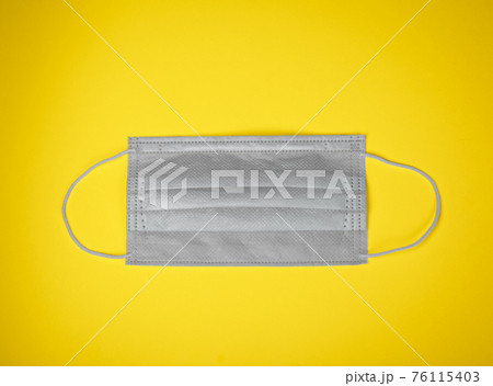 Gray medical mask on yellow background colors of the year 2021 concept 76115403