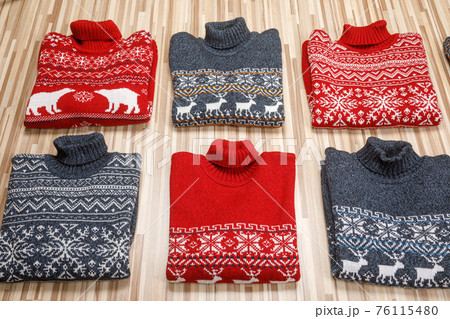 Collection of knitted Christmas turtleneck sweaters folded on wooden background 76115480