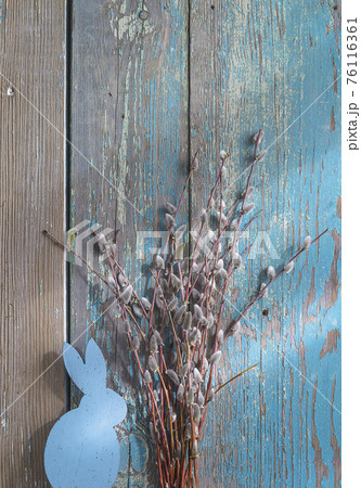 Easter holiday greeting card. Bouquet of willow and wooden bunny on old blue paint wooden background; vertical picture 76116361
